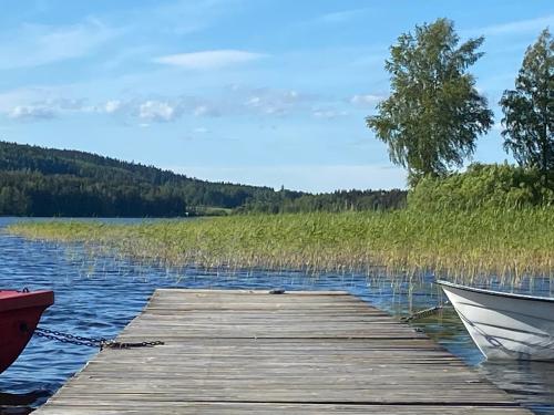 a wooden dock with a boat on a lake at Nyhyttan Nora Bergslagen The Three Birches in Nora