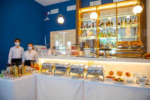 two people wearing face masks standing behind a counter in a restaurant at Newport Hotel Kutaisi in Kutaisi