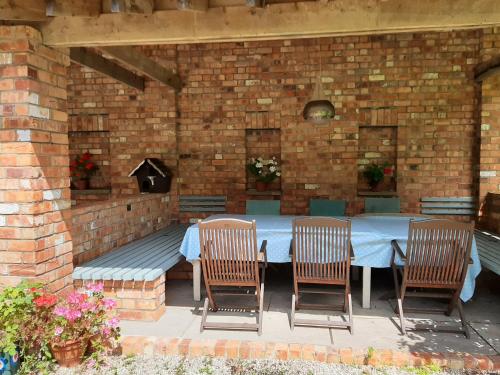 patio con mesa, sillas y pared de ladrillo en Coach House, Minting. en Horncastle