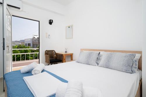 a bedroom with a large bed and a balcony at Square Studios Georgia in Matala
