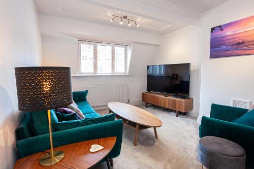 a living room with green furniture and a flat screen tv at Cosy 2 Bed Apartment - Close to Leeds Centre in Moortown