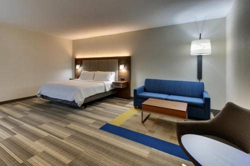 a hotel room with a bed and a blue couch at Holiday Inn Express & Suites Ithaca by IHG in Ithaca