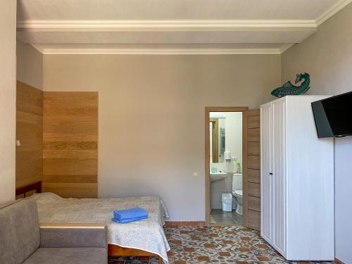 1 dormitorio con 1 cama y TV en una habitación en Uyut Guest House, en Koktebel