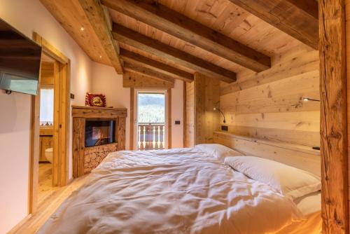 - un grand lit dans une chambre dotée de murs en bois dans l'établissement Lino Deluxe Suite, à Borca di Cadore