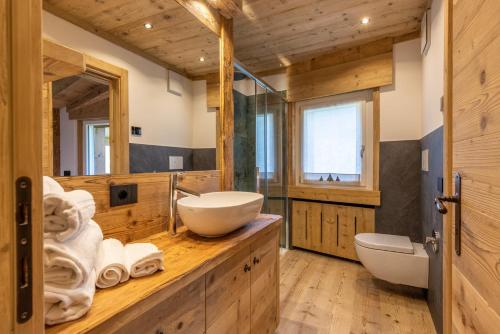 La salle de bains est pourvue d'un lavabo et de 2 toilettes sur un comptoir en bois. dans l'établissement Lino Deluxe Suite, à Borca di Cadore