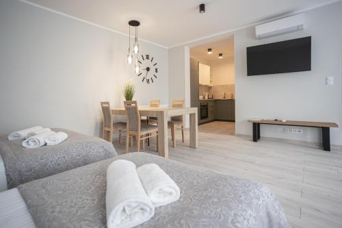 a bedroom with two beds and a dining room at Apartamenty na Chrobrego in Bydgoszcz