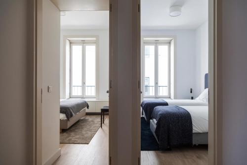 ein Hotelzimmer mit 2 Betten und 2 Fenstern in der Unterkunft Classy 2BDR Apartment in Downtown by LovelyStay in Lissabon
