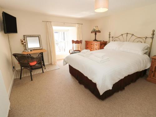 a bedroom with a bed and a chair and a television at Stable Lodge in Coldstream