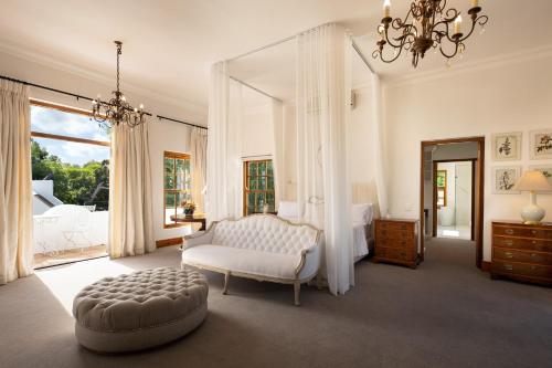 a bedroom with a bed and a chair and a mirror at Avontuur Manor House and Wine Estate in Somerset West