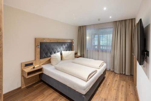a bedroom with a large bed and a television at Golf- und Sporthotel Moarhof in Walchsee