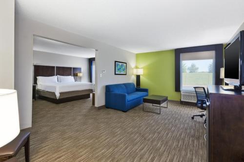 a hotel room with a bed and a blue chair at Holiday Inn Express Chillicothe East, an IHG Hotel in Chillicothe