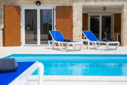 two blue and white chairs next to a swimming pool at Villa Zala in Rasopasno