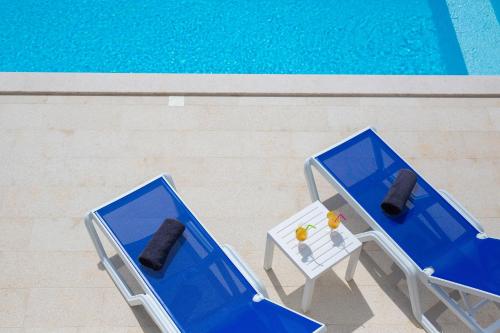 two blue chairs and a table next to a pool at Villa Zala in Rasopasno