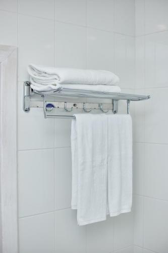 a towel rack in a bathroom with white towels at Family Hotel Happy INN in Zatoka