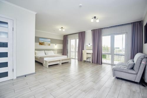 a bedroom with a bed and a couch and a chair at Family Hotel Happy INN in Zatoka