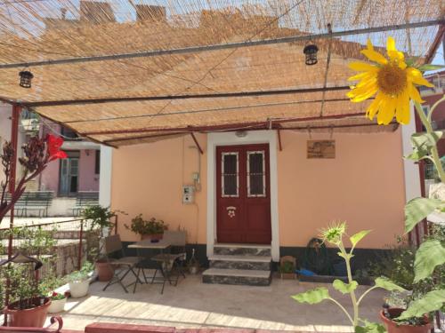 una casa con una puerta roja y un girasol en The Village Cottage - Benitses en Benitses