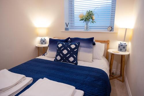 ein Schlafzimmer mit einem blauen und weißen Bett mit zwei Lampen in der Unterkunft Stylish Brixham Apartment - Free on street parking in Brixham