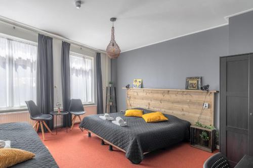 a bedroom with a bed and some chairs and windows at Hotel Café Restaurant 't Raedhûs in Dokkum
