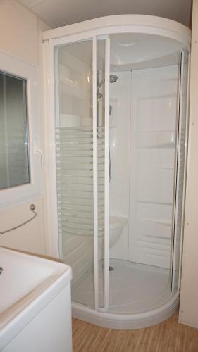 une salle de bain blanche avec une douche et un lavabo dans l'établissement Chalets met buitenkeuken op Camping Leï Suves - JoyCasa, à Roquebrune-sur Argens