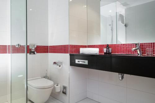 a bathroom with a toilet and a sink and a mirror at OREA Hotel Angelo Praha in Prague