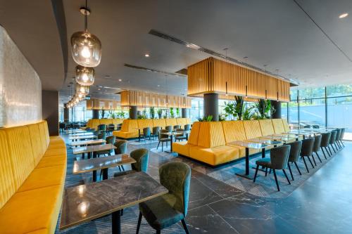 a restaurant with yellow chairs and tables and benches at Grand Hotel Esztergom in Esztergom