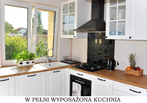 a kitchen with white cabinets and a stove top oven at Bulwar Gdynia in Gdynia