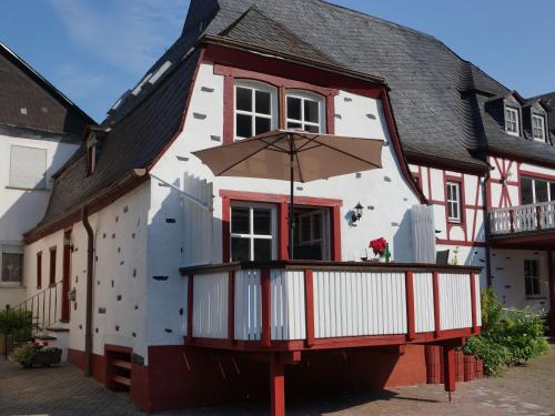 a white and red building with a balcony with an umbrella at Altes Fährhaus an der Mosel anno1633 in Traben-Trarbach