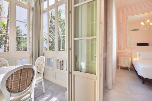 - une chambre avec une table et des chaises dans l'établissement Tandem Palacio Veedor de Galeras Suites, à Cadix