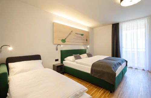 a hotel room with two beds and a window at JUFA Hotel Laterns - Klangholzhus in Laterns