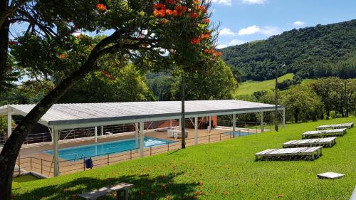 uma casa grande com piscina e espreguiçadeiras em O Recanto Pousada em Serra Negra