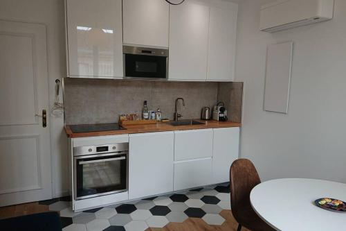 - une cuisine avec des placards blancs, une table et un évier dans l'établissement appartement 4 pers quartier Chartrons à Bordeaux, à Bordeaux