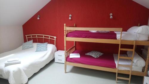 a bedroom with two bunk beds and a red wall at Auberge des lacs in Massignac