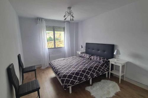 a bedroom with a bed and a chair and a window at Apartamento la Fortaleza in San Vicente de la Barquera