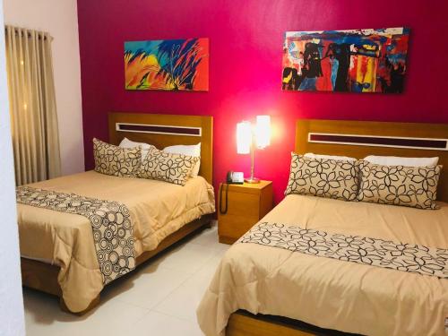 a bedroom with two beds and a pink wall at Dpravia Hotel SRL in Baní