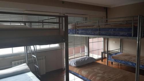 3 Etagenbetten in einem Zimmer mit Fenster in der Unterkunft Albergue en Corcubion playa de Quenxe in Corcubión