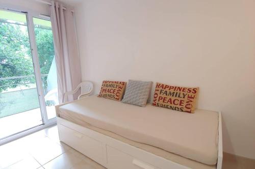 - un canapé blanc dans une chambre avec fenêtre dans l'établissement Le Petit Nid Perché, à Arles