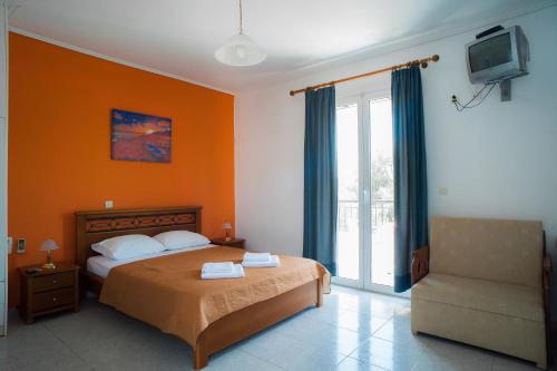 a bedroom with a bed and a television and a chair at Marmaron Rooms in Agiokampos