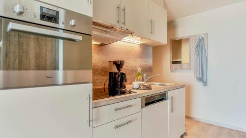 a kitchen with white cabinets and a sink at Holiday Suites Blankenberge in Blankenberge