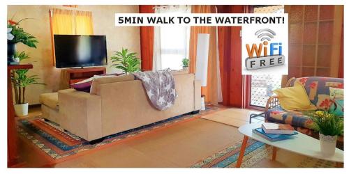 a living room with a couch and a tv at WOODY Pt - AMAZING 1970's SHARE HOUSE BY THE SEA-4 rooms available! in Woody Point