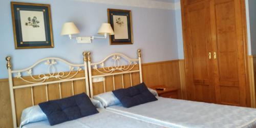 a bedroom with a bed with two blue pillows on it at Hosteria Gante in Jarandilla de la Vera