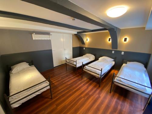 two beds in a room with wooden floors at Xplore Hostel Amsterdam in Amsterdam