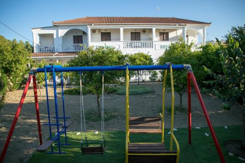a playground in a yard with a house in the background at Studio Stars in Laganas