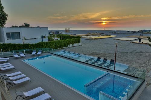 a swimming pool with chairs and the ocean at sunset at Jijo's Hotel in Mamaia