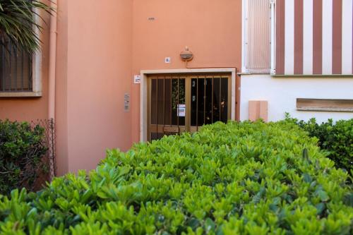 a door to a building with green bushes in front at Las Floridas Apartment in Alghero