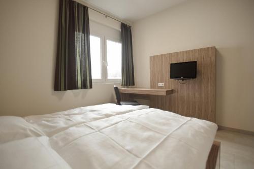 a bedroom with a bed and a desk and a television at Hotel Maxis in Karlsbad