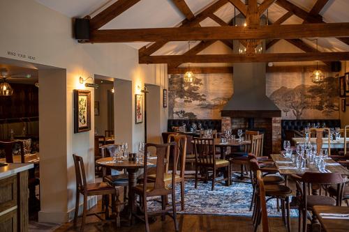 restauracja ze stołami i krzesłami oraz kominkiem w obiekcie The Filly Inn w mieście Brockenhurst