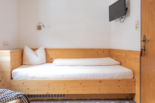 a bedroom with a wooden bed with a tv on the wall at Landhaus Fiegl in Sölden