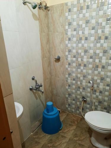 a bathroom with a toilet and a shower with a blue stool at Royal Suvarna Comforts in Mysore