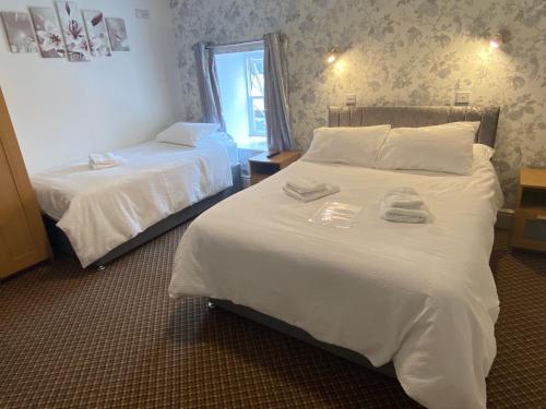 a hotel room with two beds and a mirror at The Roebuck Inn in Chapel en le Frith