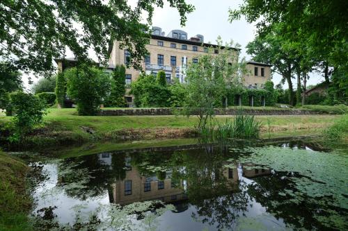 a building reflecting in a pond in front of a building at Gutshaus Redewisch Hotel & Restaurant in Boltenhagen